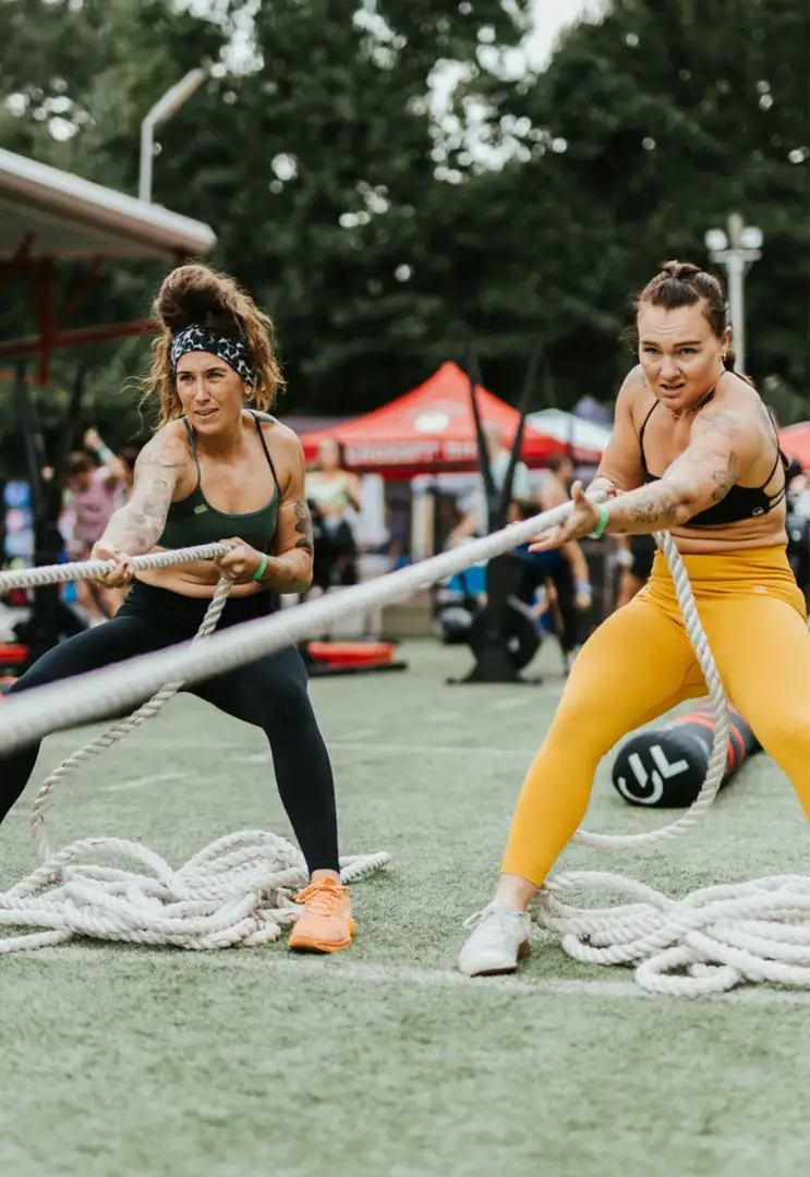 Two woman pull on ropes during a Fit Fest competition